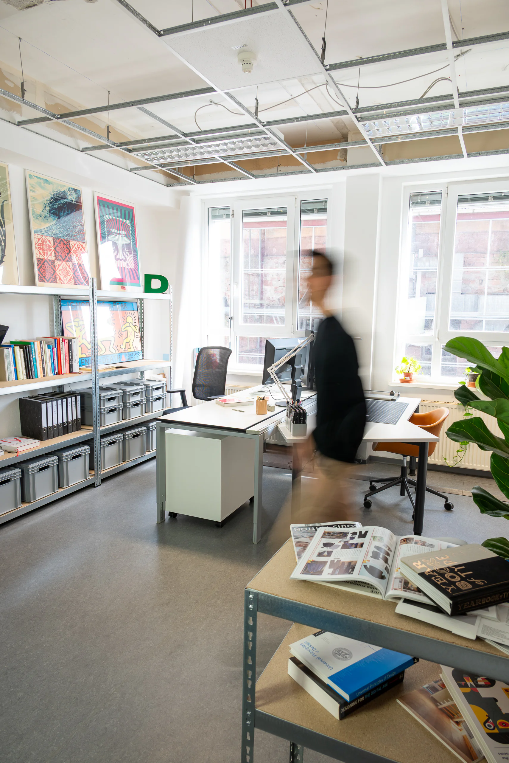 Das Studio leokawa in Frankfurt, Arbeitsplätze mit Regal und Plakaten.
