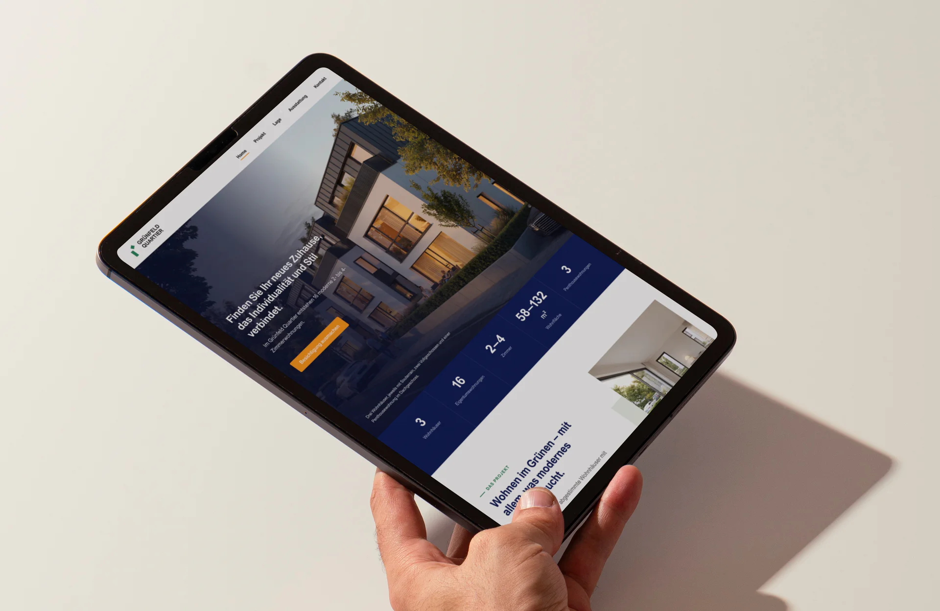 Ein Tablet in der Hand, darauf die Startseite des Quartier Grünfeld mit einem der Häuser in der Abendsonne.